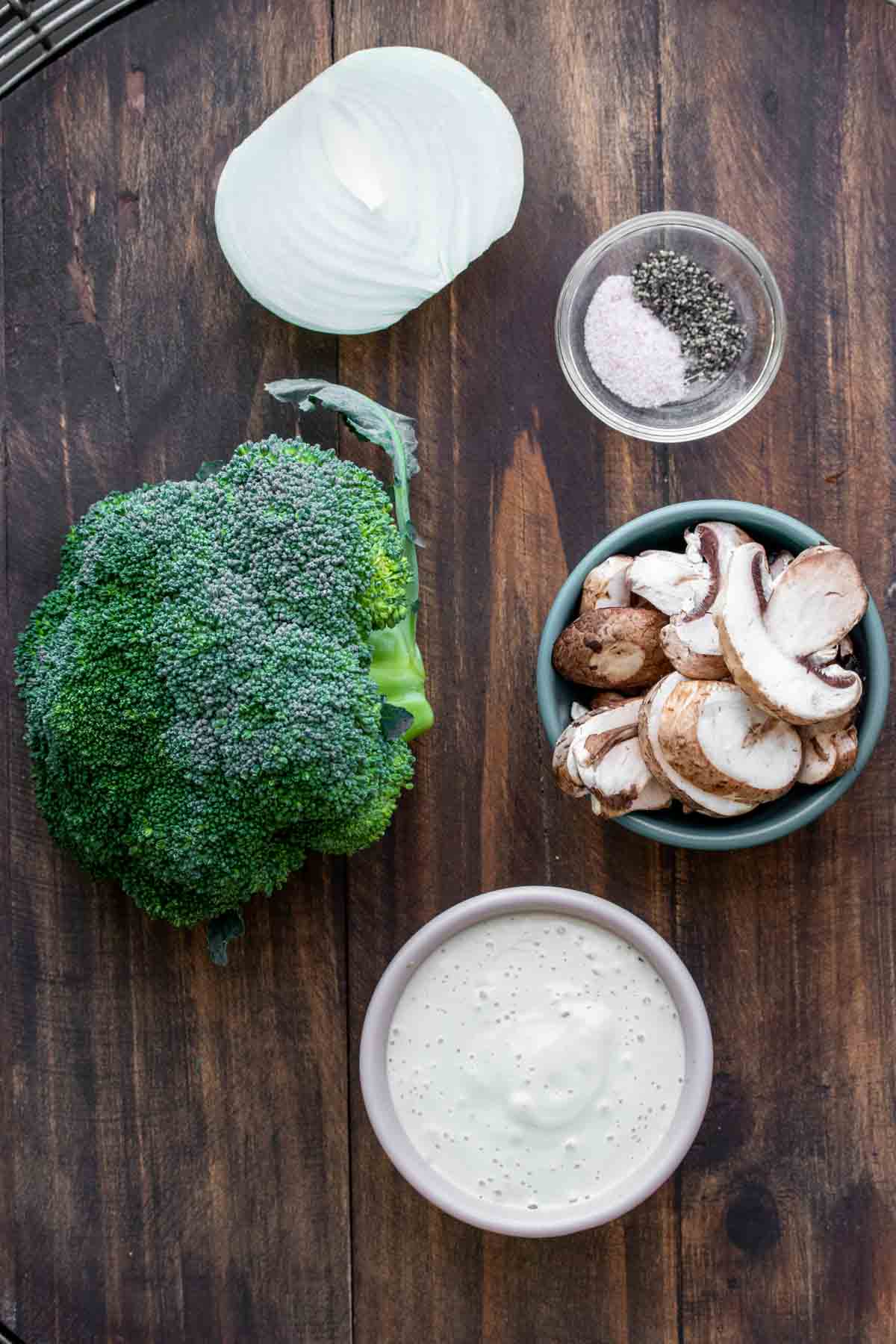 Ingredients needed to make a creamy broccoli casserole on a wooden surface.