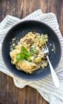 A cream based broccoli casserole with mushrooms and breadcrumb topping in a blue bowl.