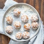 Grey bowl filled with shredded coconut covered energy balls.