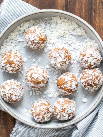 Grey bowl filled with shredded coconut covered energy balls.