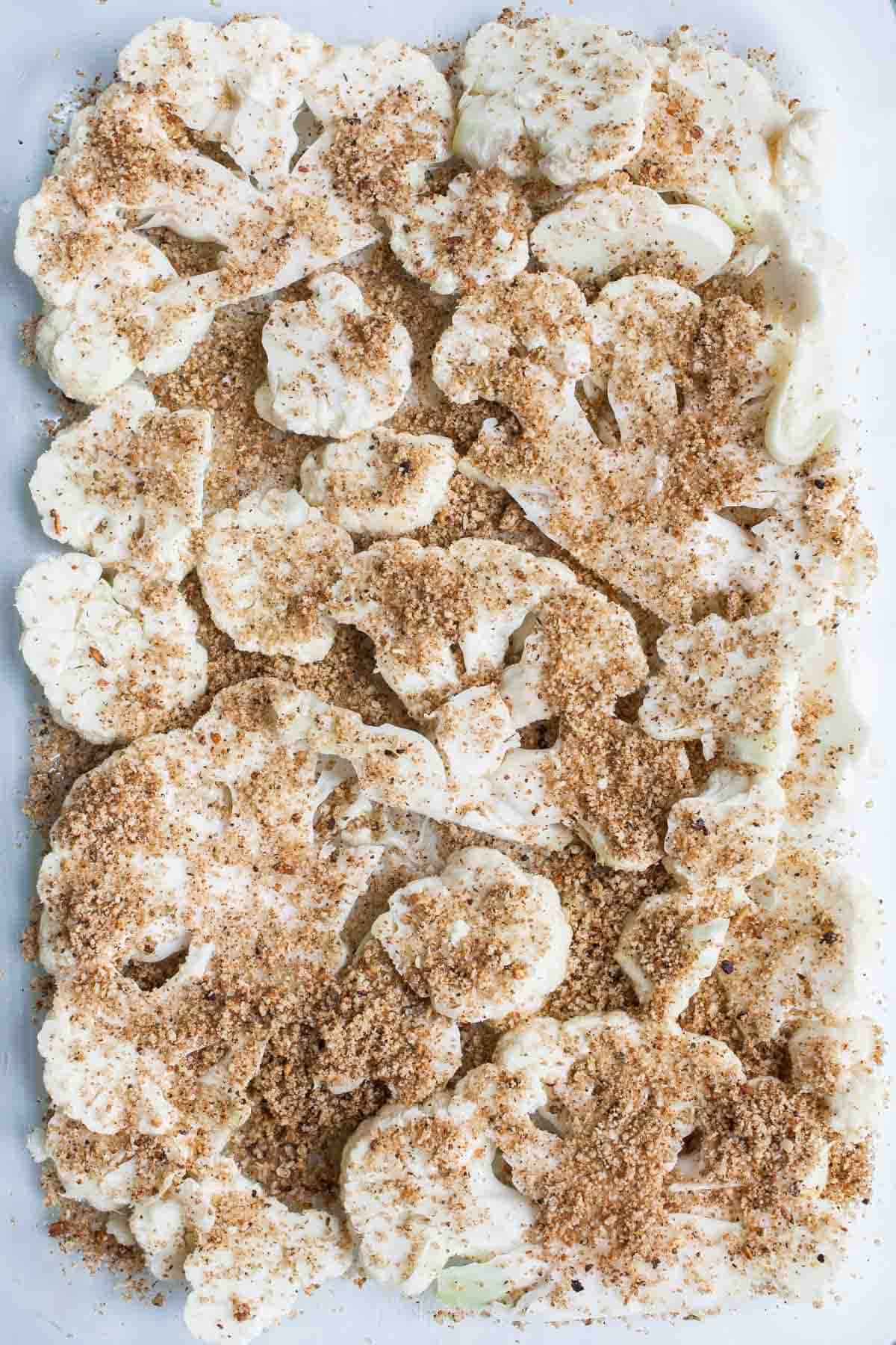 Slices of cauliflower covered with breadcrumb topping in a baking dish.