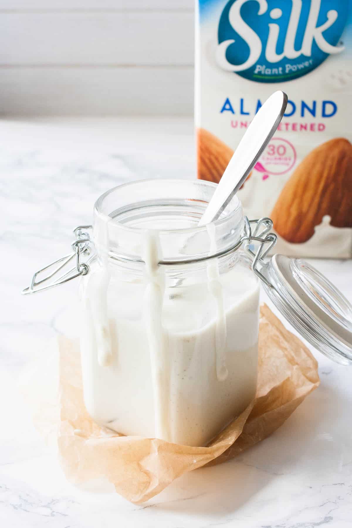 A jar with creamy white sauce in it on a kitchen counter.