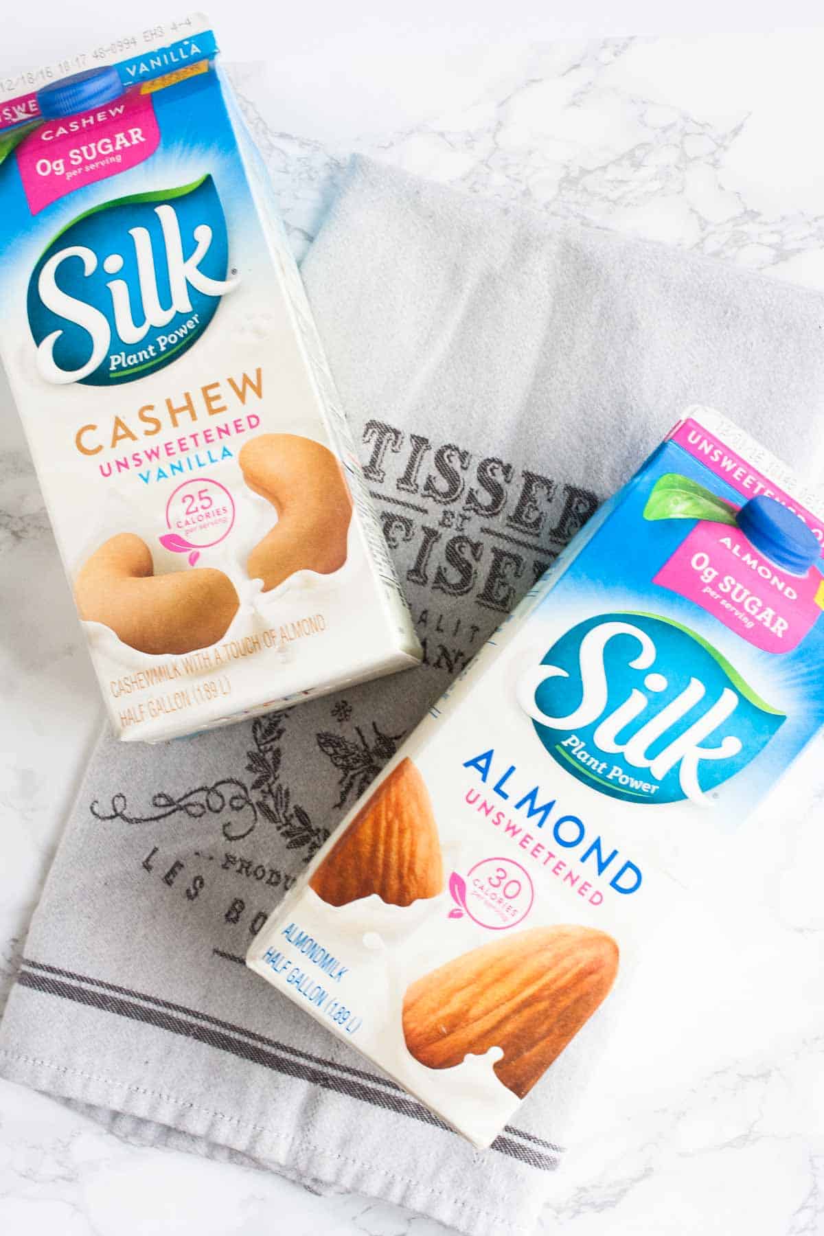 Silk dairy free milk containers laying on a grey towel.