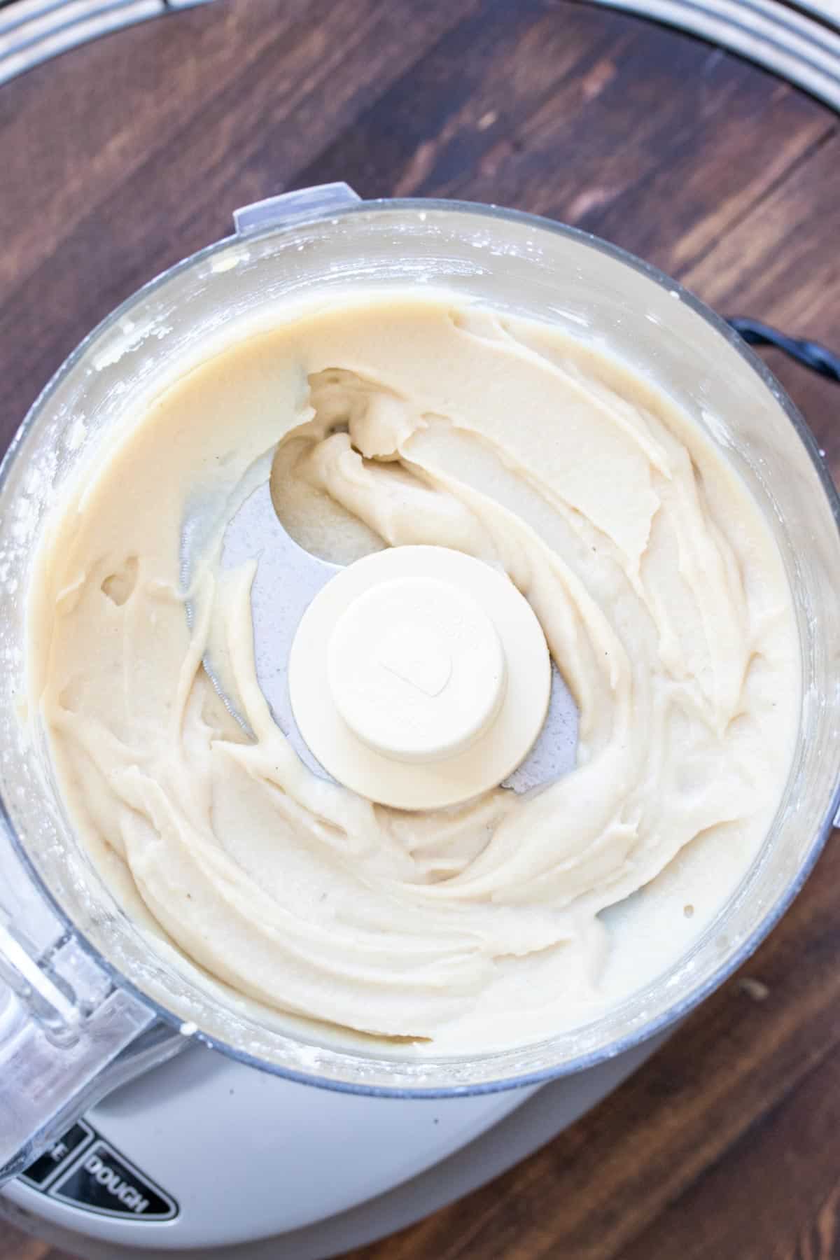 Top view of a food processor with a blended cream cheese frosting inside