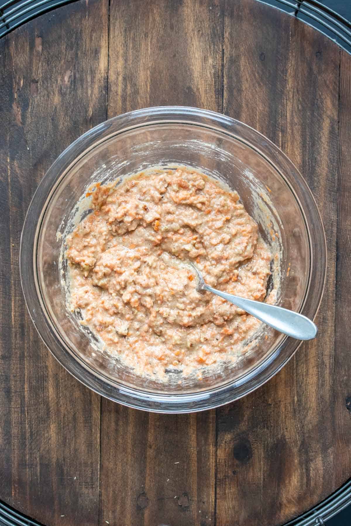 Carrot cake batter in a glass bowl with a spoon