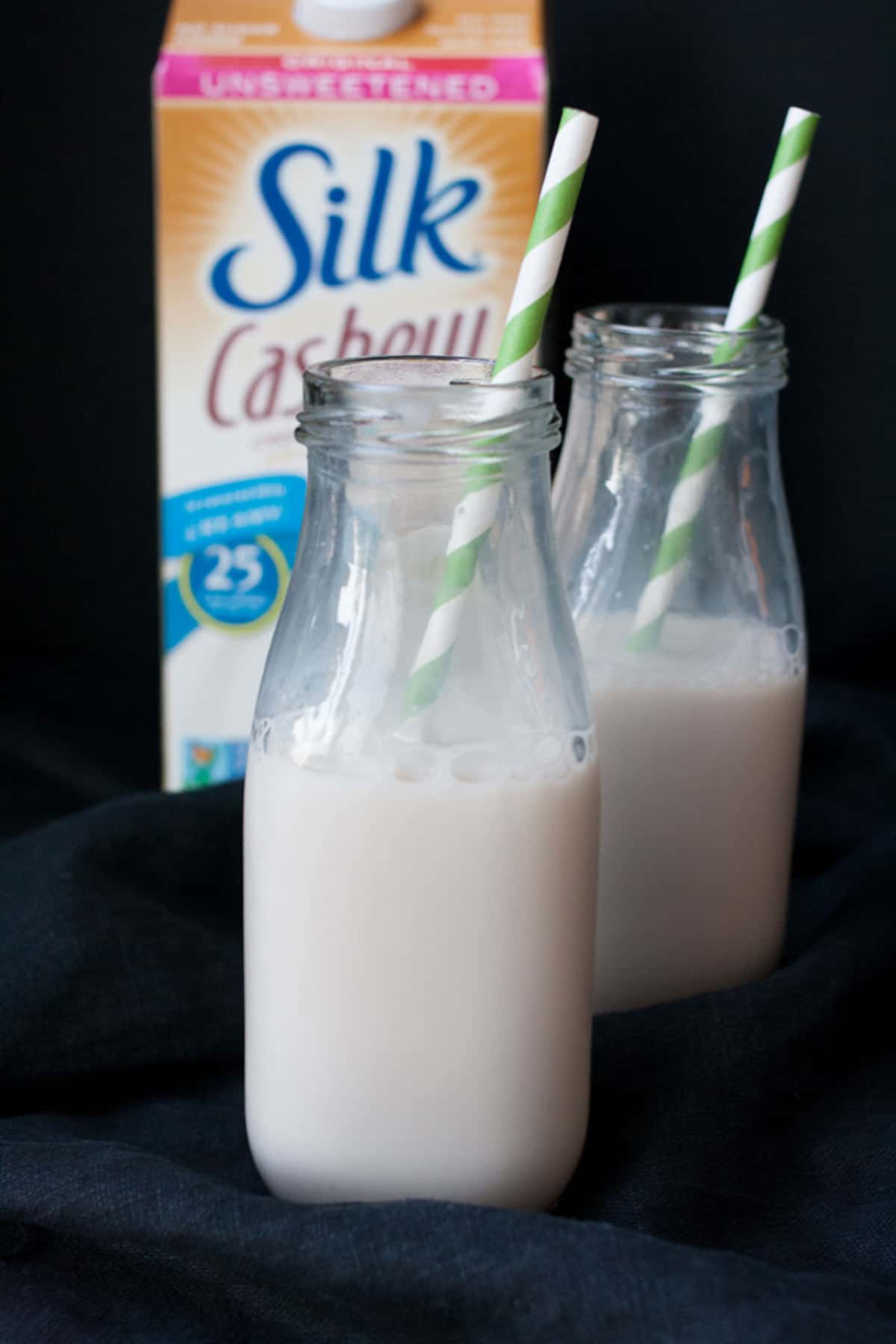 Two glass milk jars with cashew milk inside of them