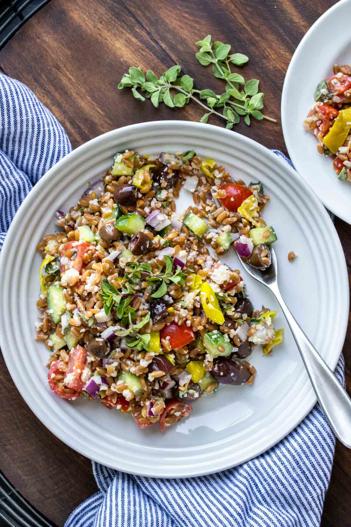 Fork on white plate with Greek farro salad on a wooden table