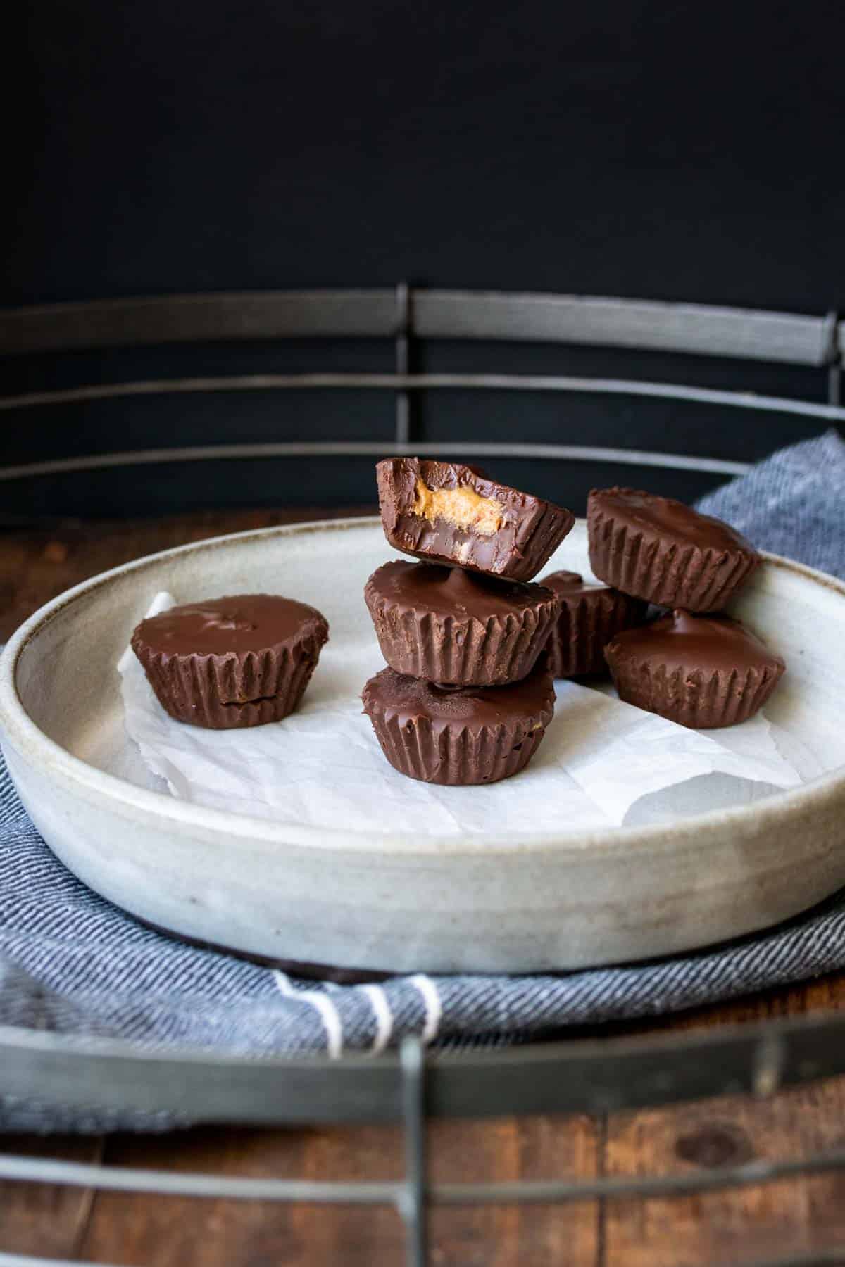 Pile of peanut butter cups on a grey plate and one with a bite out of it