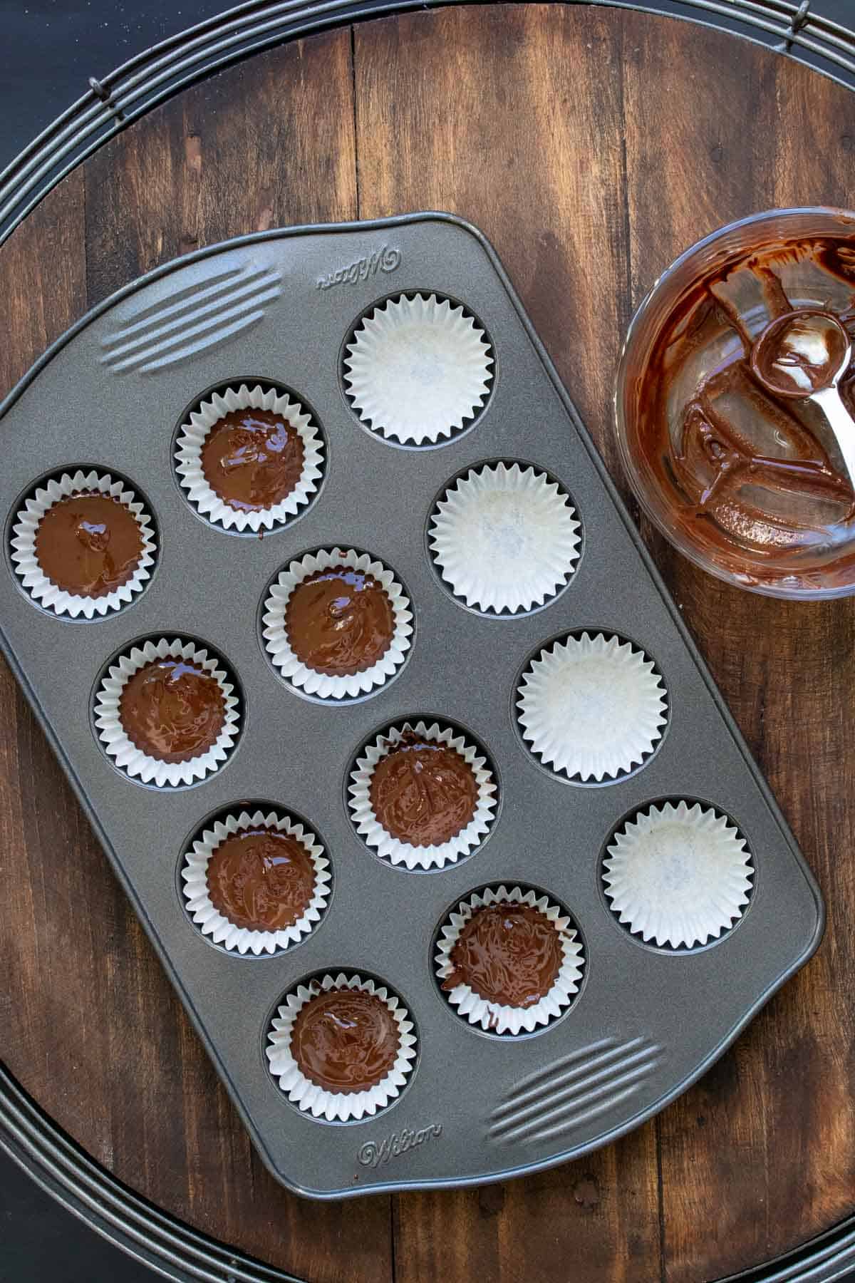 Mini muffin tin filled with liners and melted chcocolate