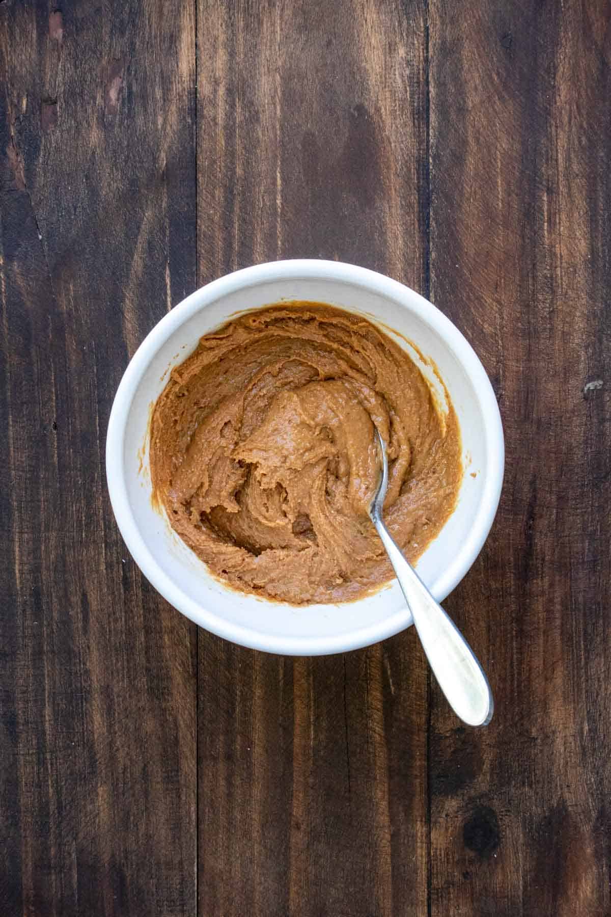 White bowl with a spoon mixing a peanut butter mixture in it