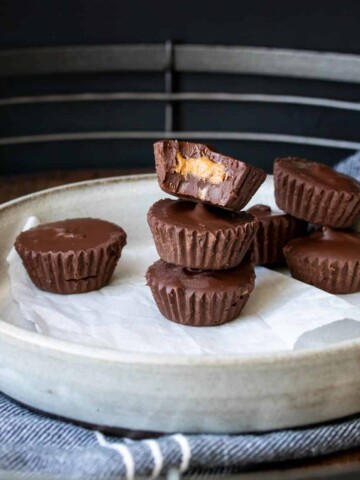 A bitten peanut butter cup on top of a pile of other peanut butter cups