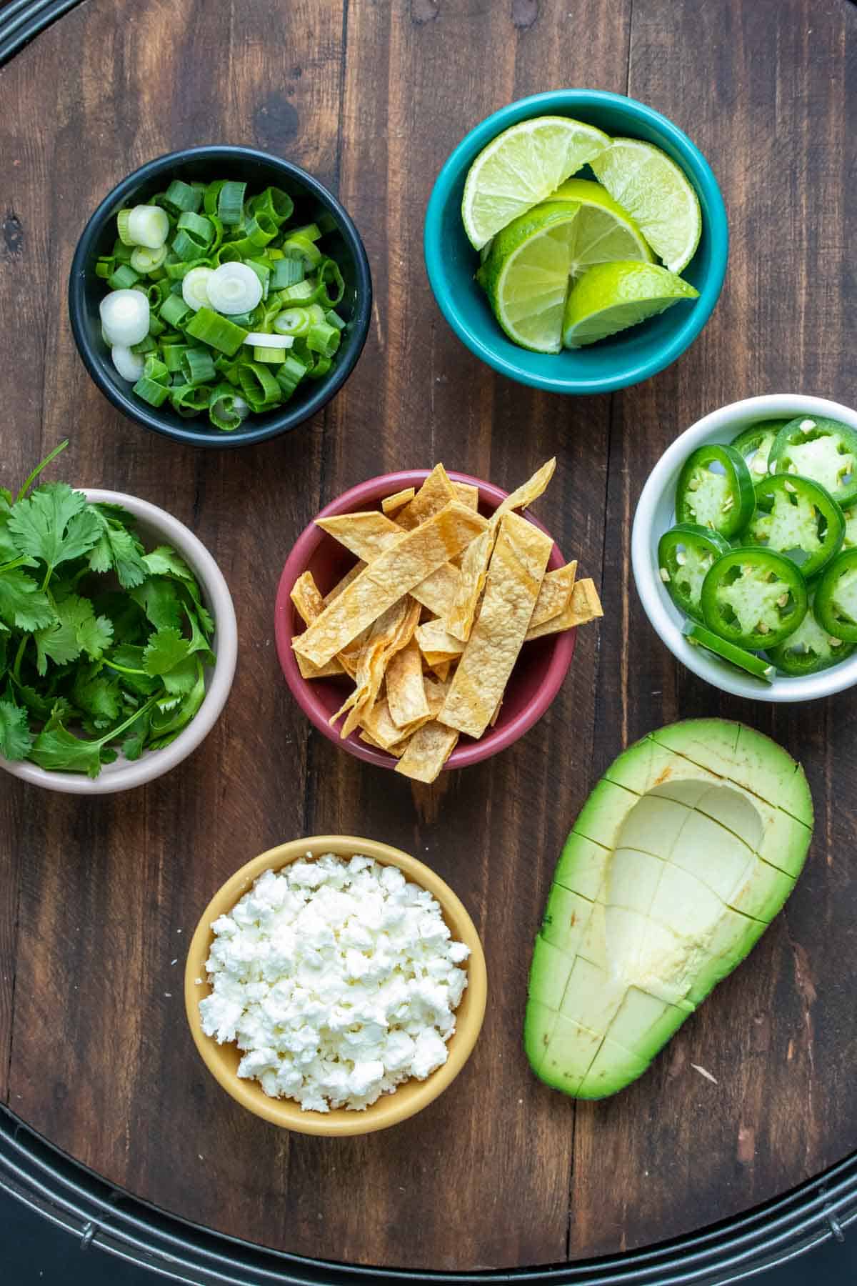 Toppings for tortilla soup sitting on a wooden surface