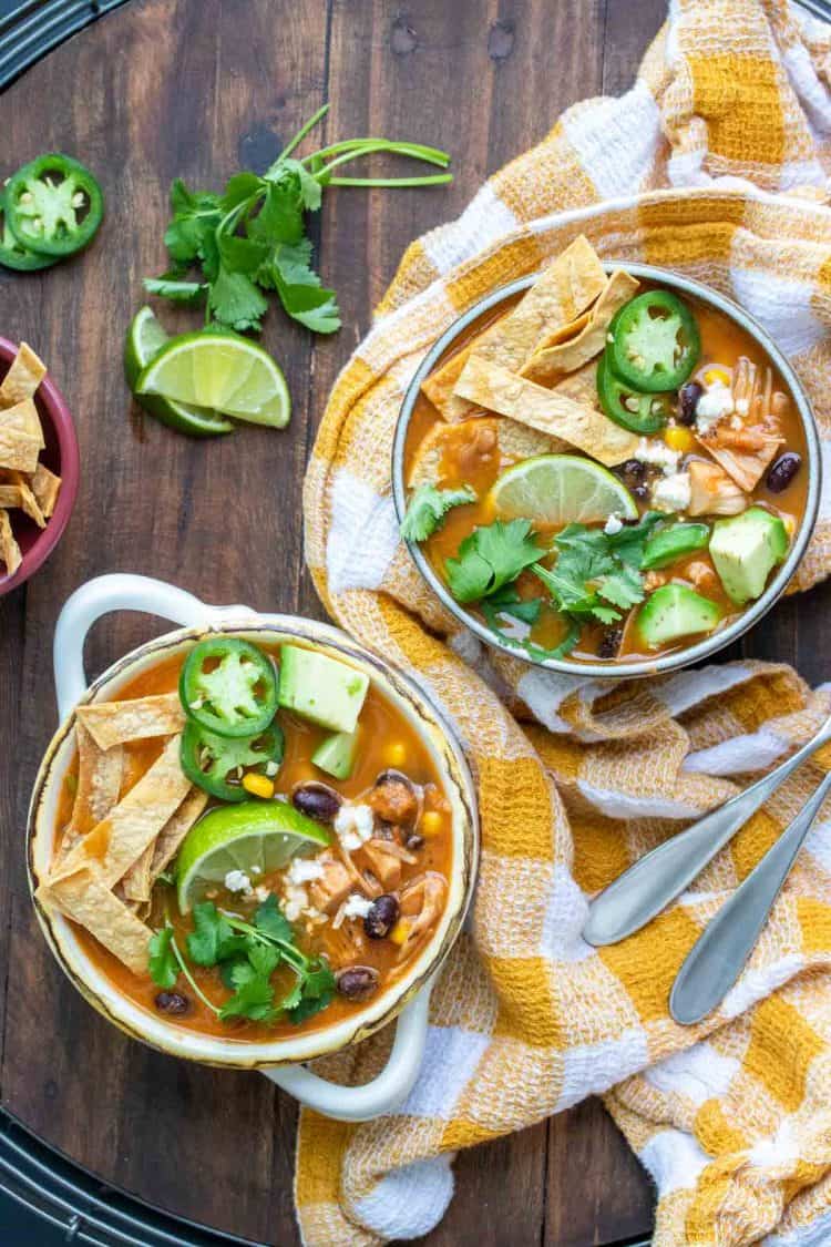 Two bowls filled with tortilla soup and loaded with toppings