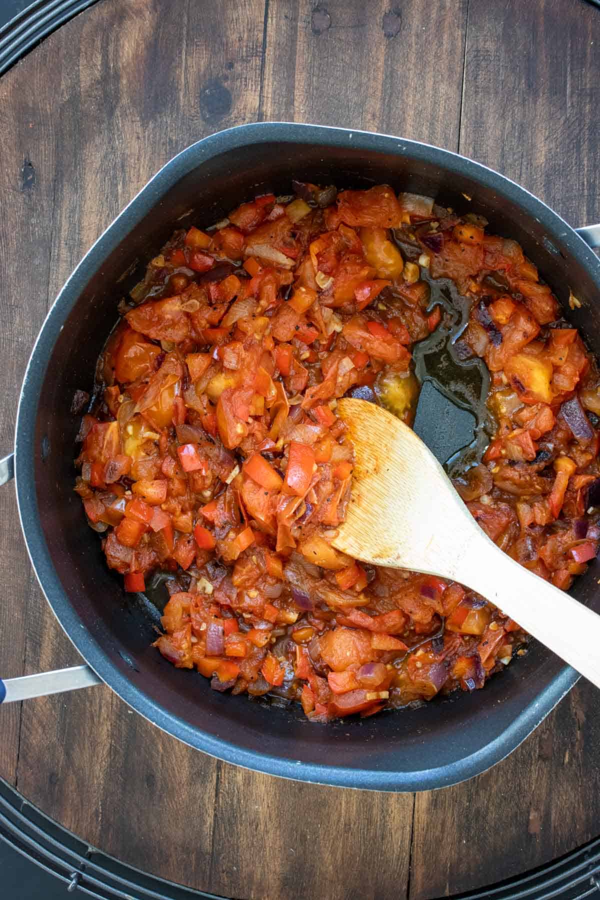 Wooden spoon mixing tomato mix in a pot