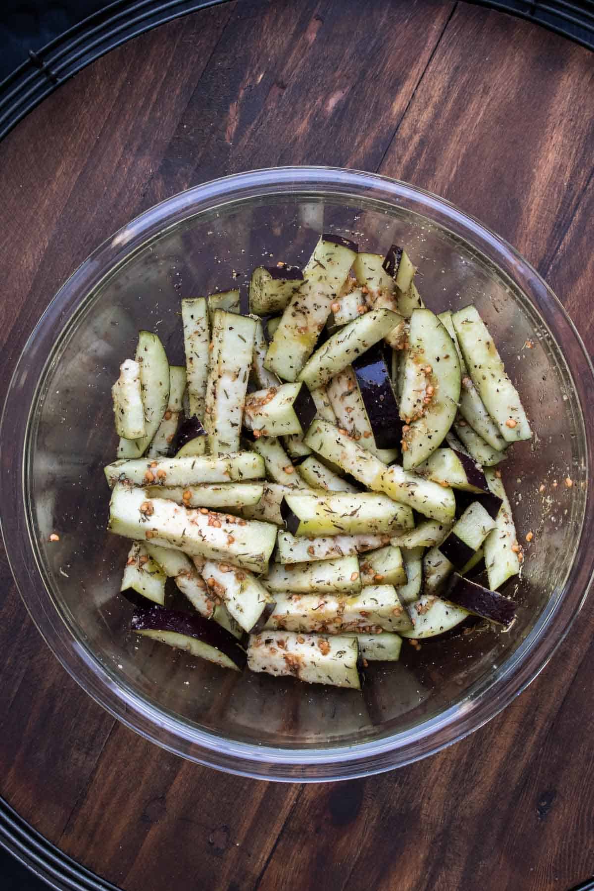 Glass bowl with fry shaped eggplant pieces covered in spices.