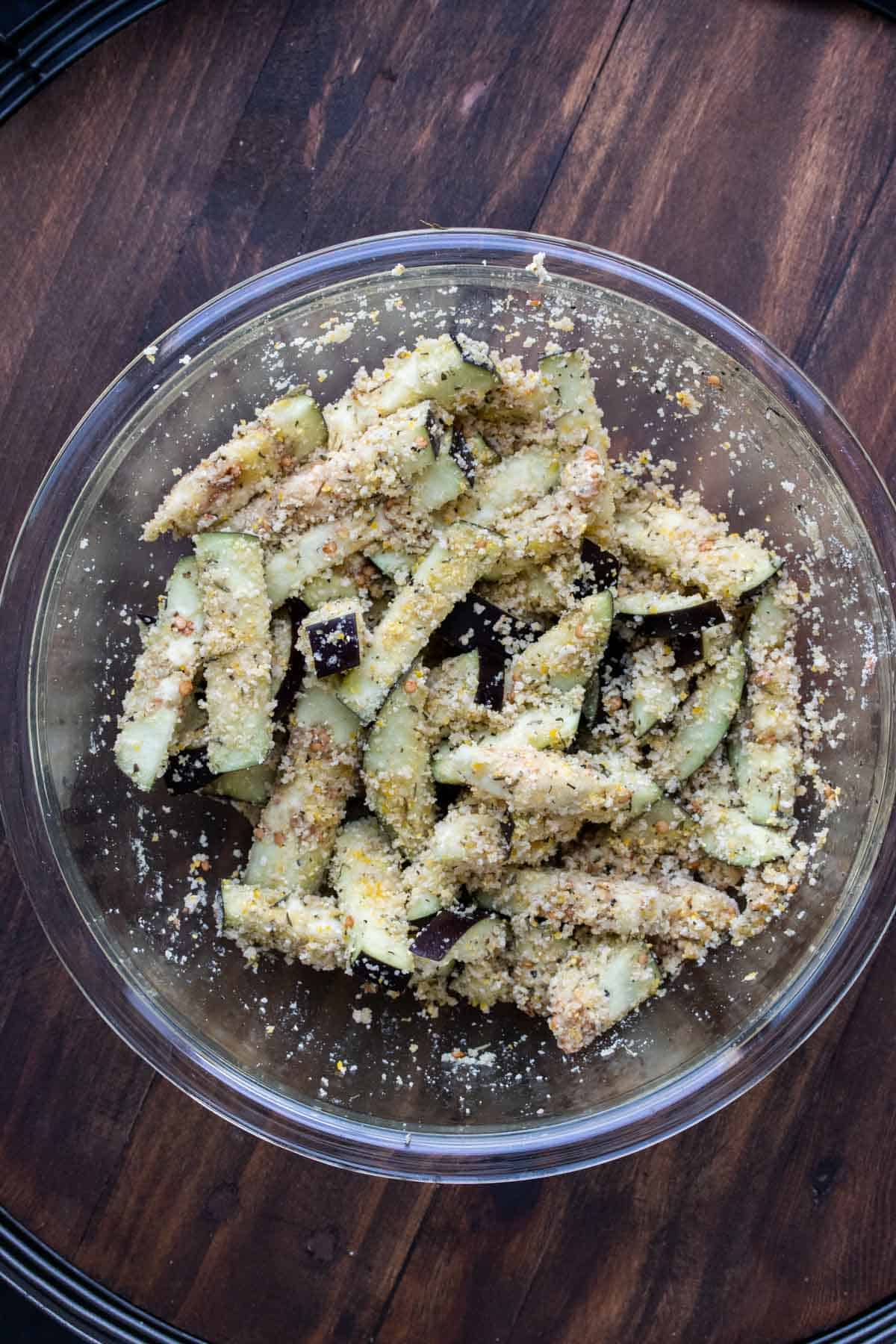 Eggplant sticks covered in crispy topping in a glass bowl