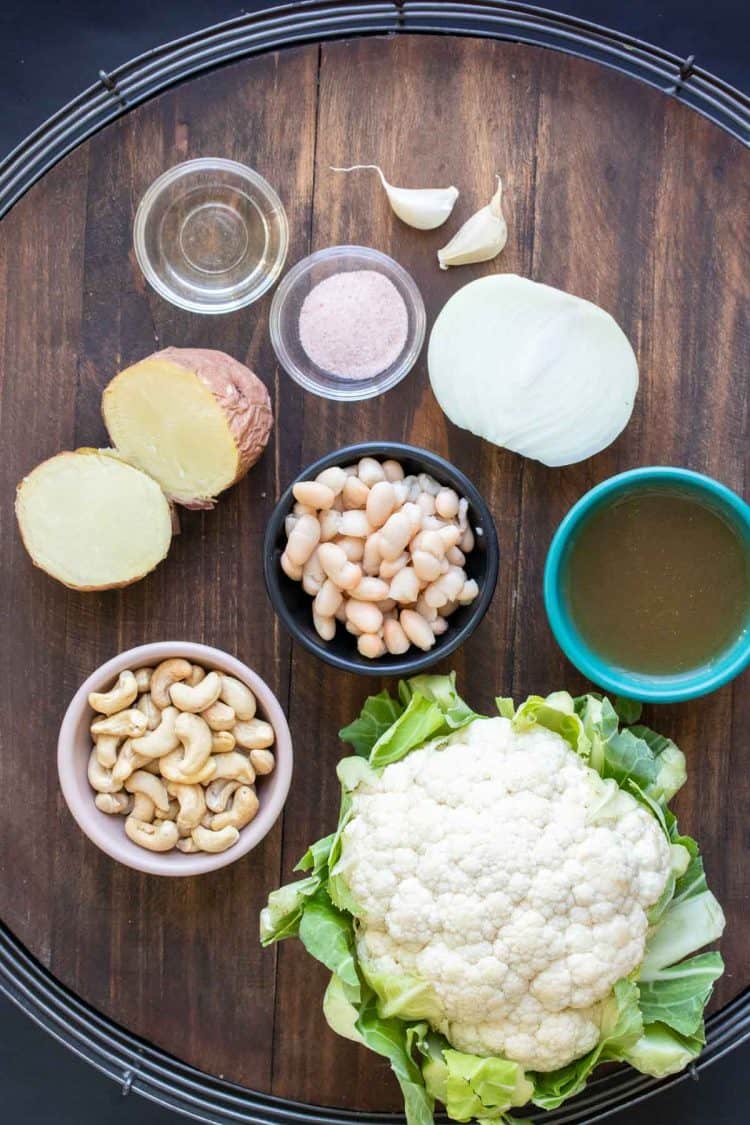 Ingredients needed to make a dairy free cauliflower soup on a wooden surface