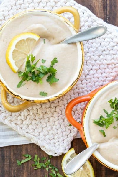 Yellow and orange soup bowls filled with cauliflower soup and sprinkled with chopped parsley