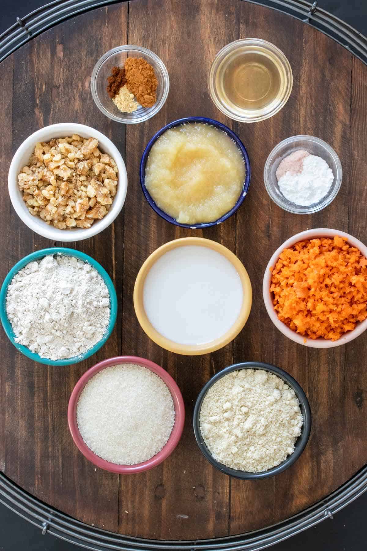 Different colored bowls filled with ingredients to make carrot cake energy balls