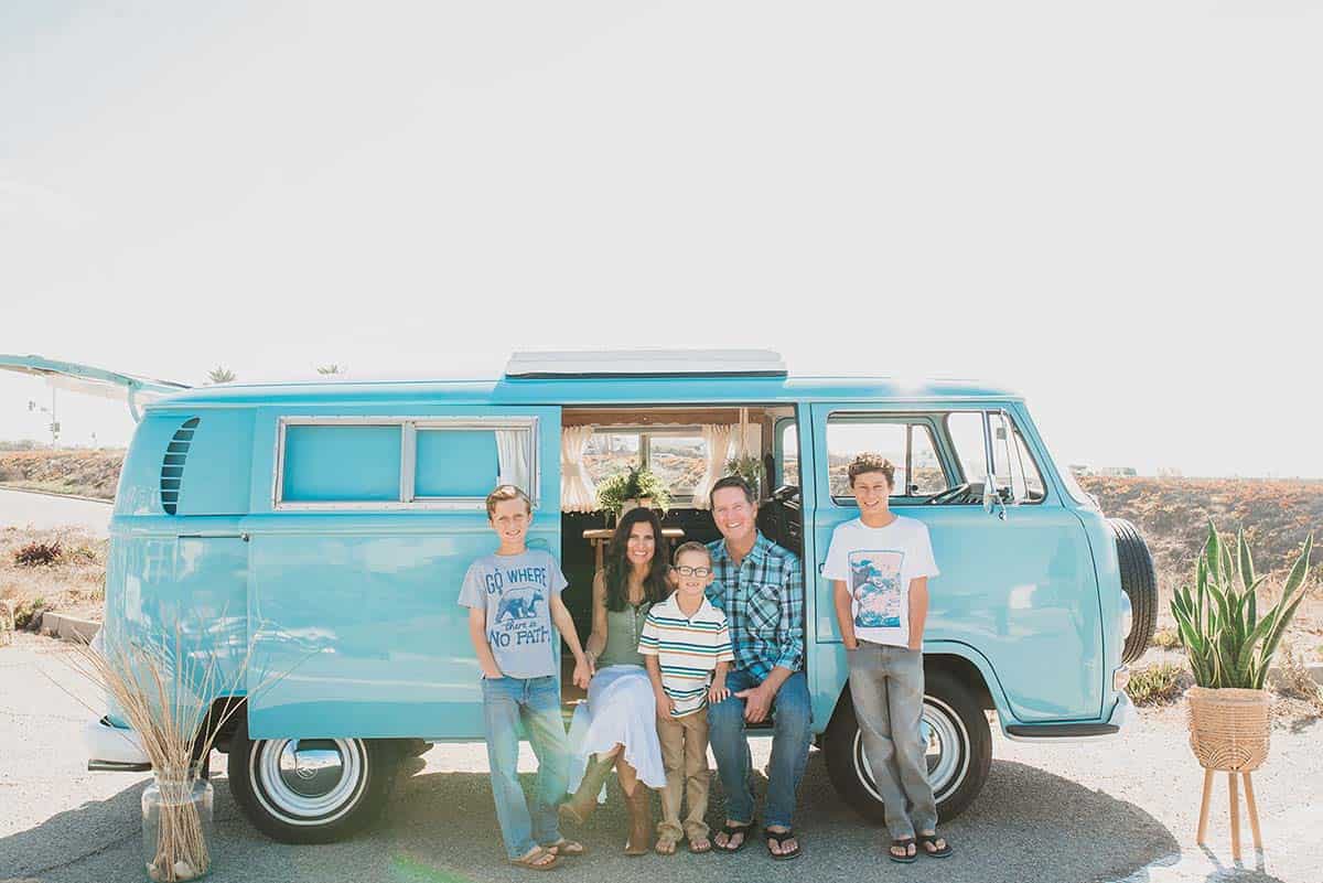 Photo of family sitting on a white wall and laughing.