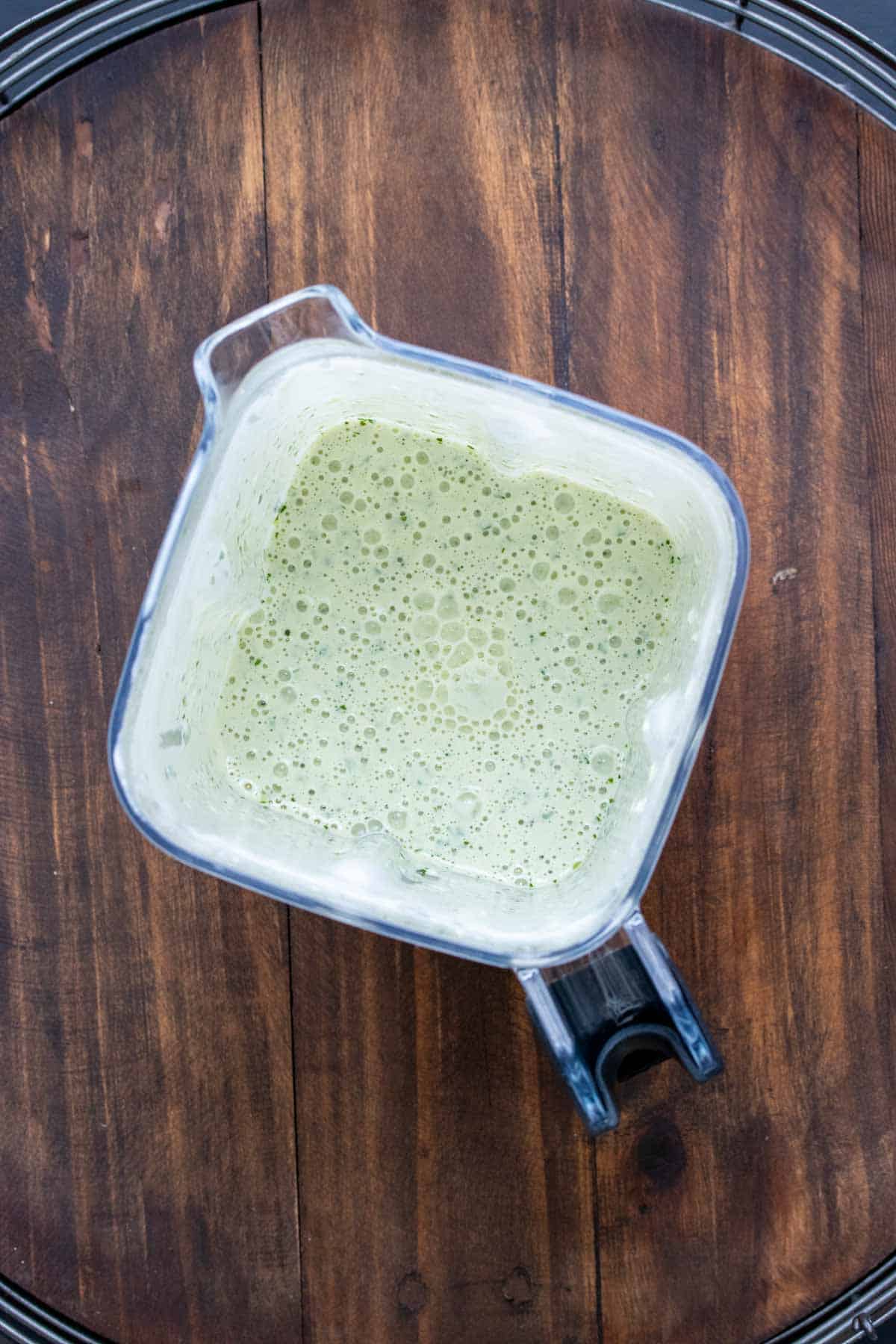 Top view of a blender with a light green creamy sauce