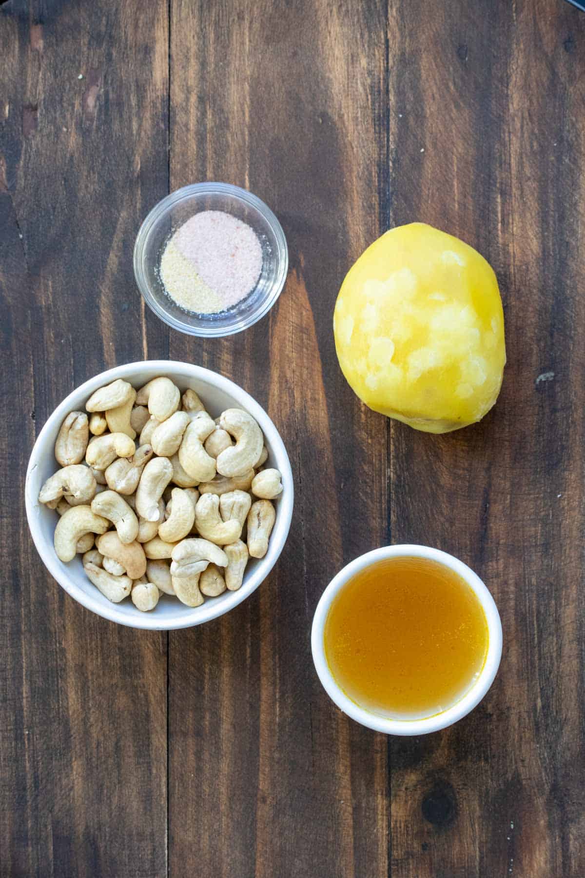 A bowl of cashews, broth and salt with a cooked potato