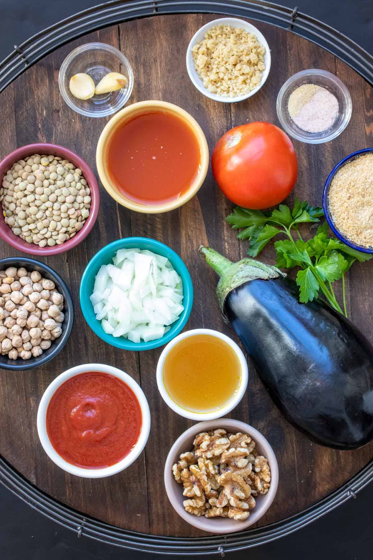 Wooden tray with ingredients for lentil based moussaka laying on it and some in bowls