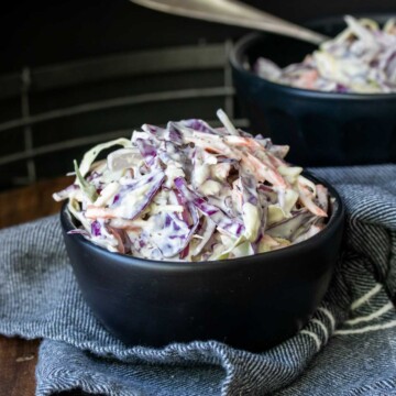 Black bowl filled with coleslaw on a blue napkin