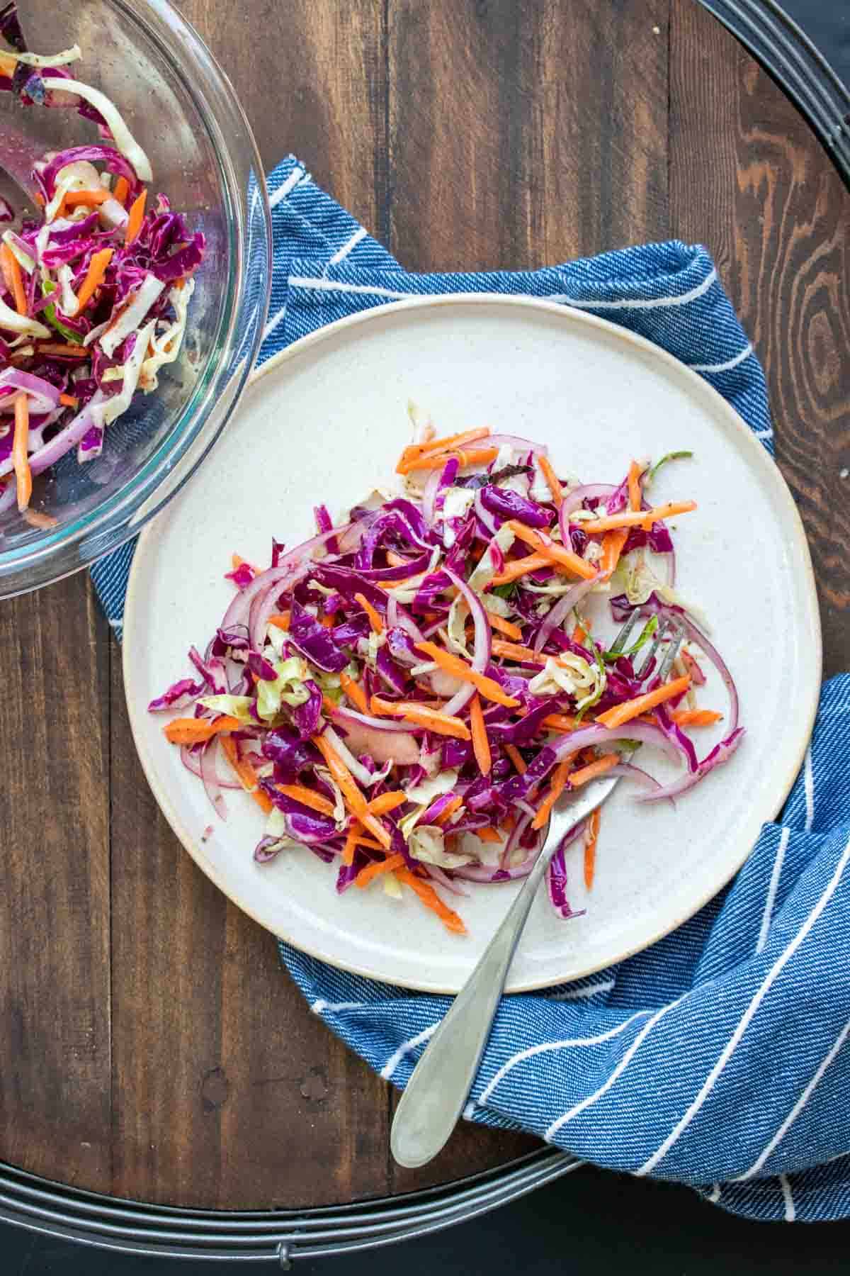 White plate with a fork in a pile of cabbage slaw