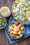 Top view of bowls of salad, croutons, microgreens and dressing