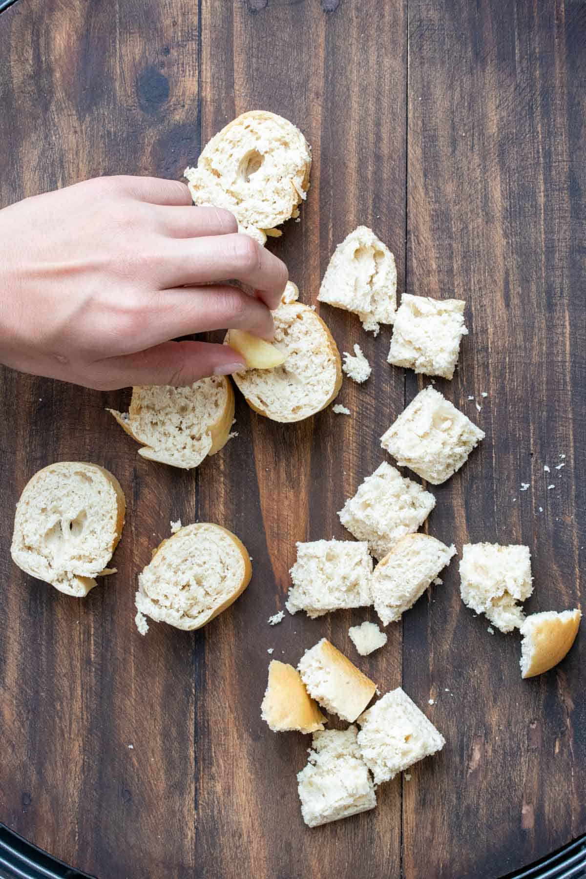 Hand rubbing cut garlic on cubes of bread