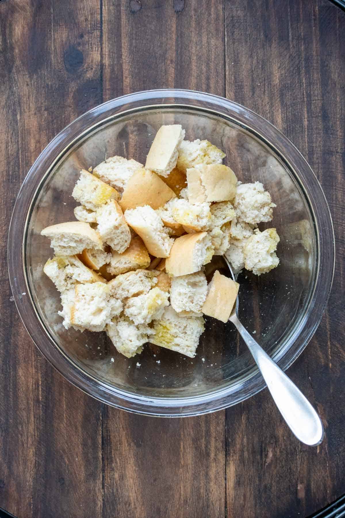 Cubes of bread in a glass bowl with a spoon