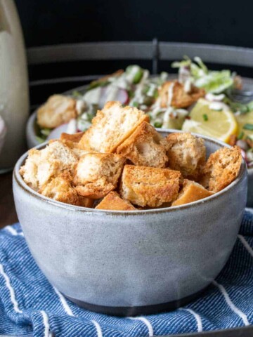 Baked crispy croutons in a grey bowl on a blue striped napkin