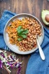 A grey plate filled with half Mexican rice and half pinto beans