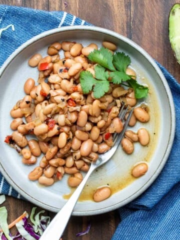 Grey plate filled with pinto beans topped with sprigs of cilantro