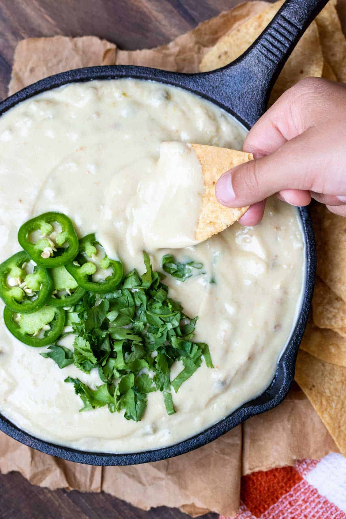 Top view of chip being dipped into white queso dip