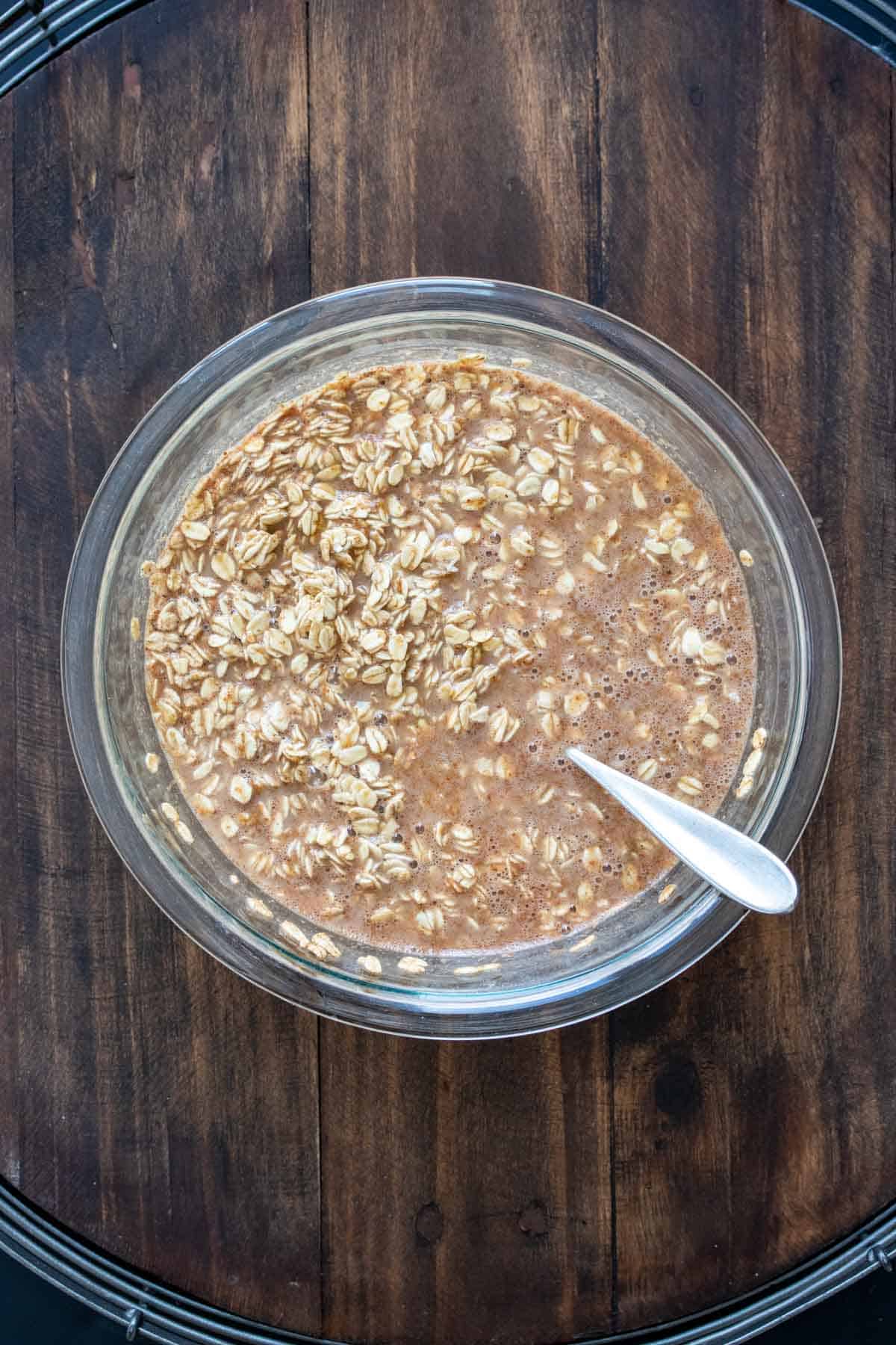 Glass bowl with oats and milk being mixed with a spoon