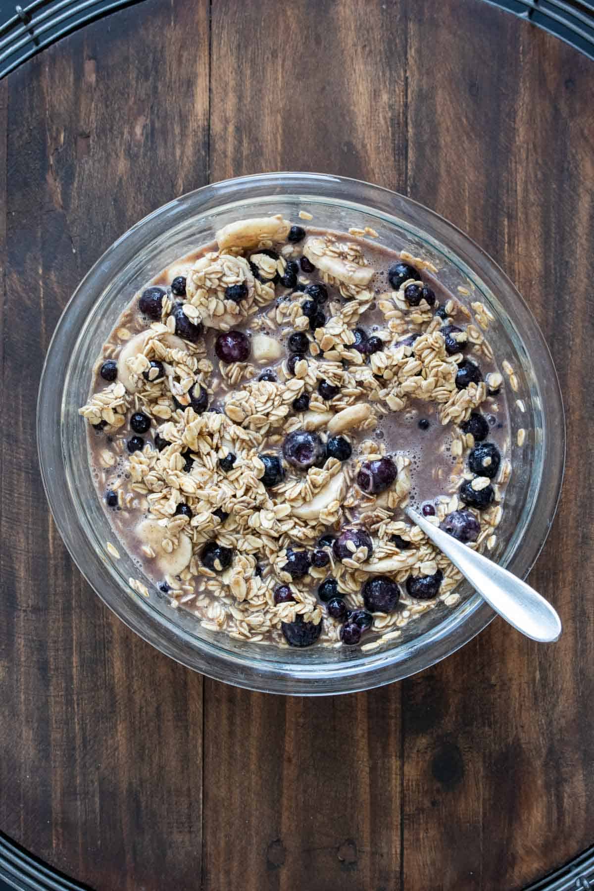 Oats, blueberries and milk in a glass bowl on a wooden surface