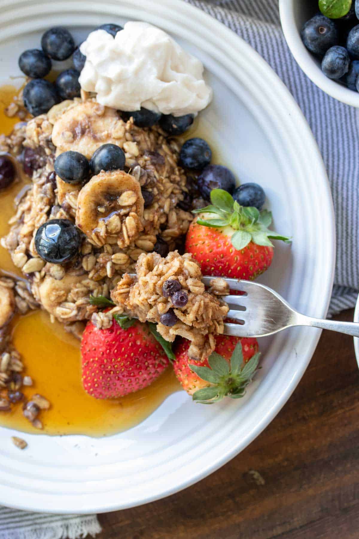 Fork getting a bite of baked oatmeal with blueberries, bananas and strawberries