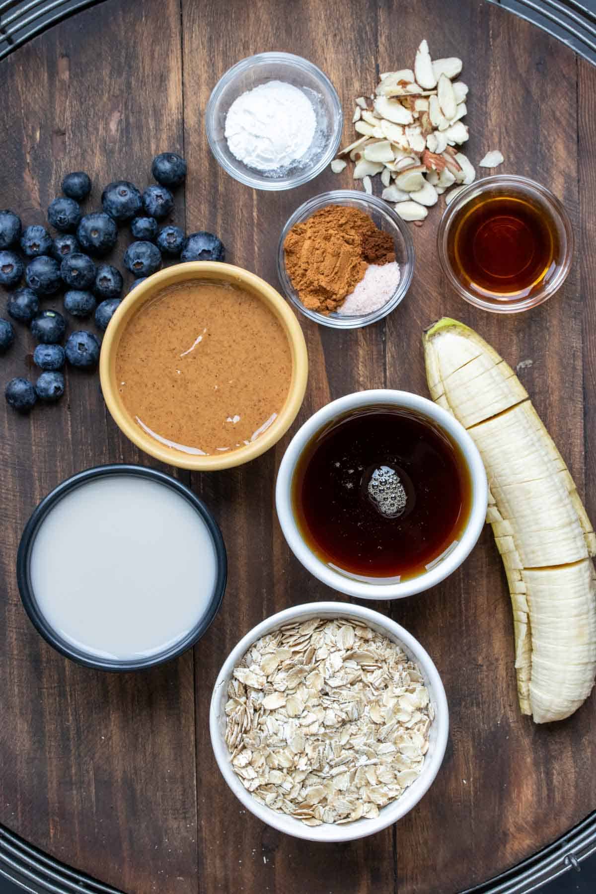 Ingredients needed to make a blueberry and banana baked oatmeal sitting on a wooden surface