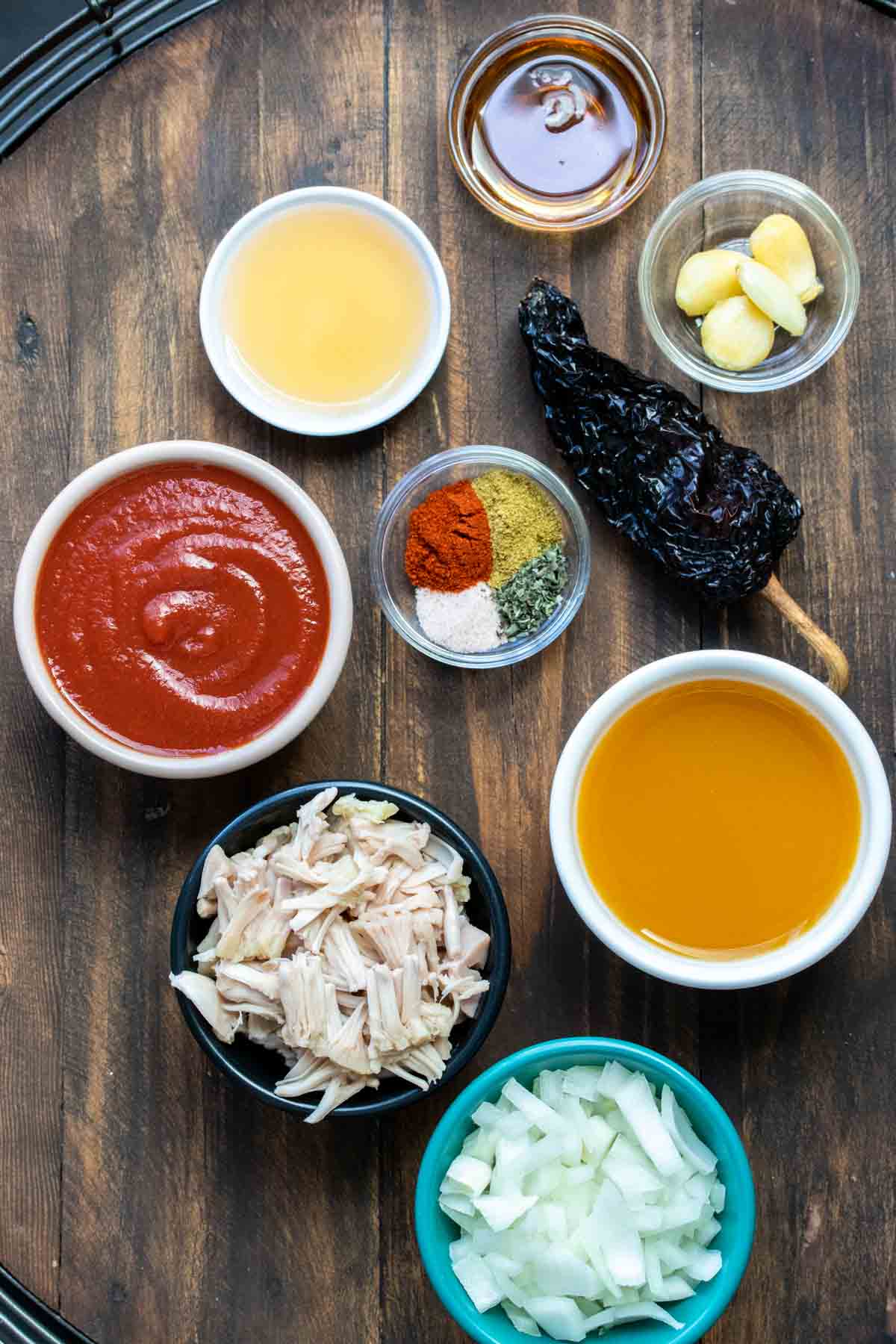 Different colored bowls with ingredients needed to make jackfruit birria tacos on a wooden table