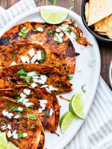 White platter with five pan fried birria tacos on it