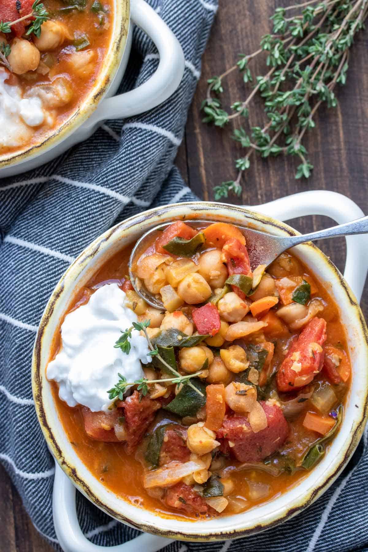 Spoon getting a scoop of veggie and chickpea stew from a bowl.