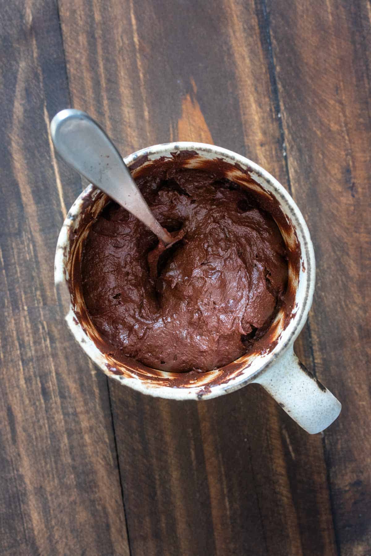 Top view of chocolate cake batter in a cream mug