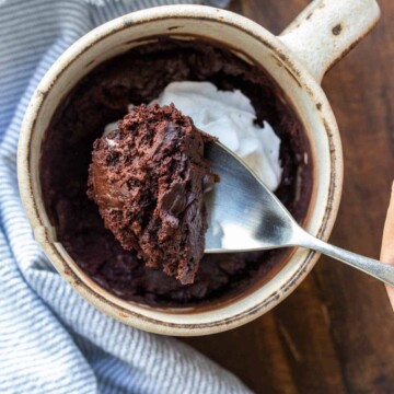 Spoon getting a bite of chocolate cake from a cream mug