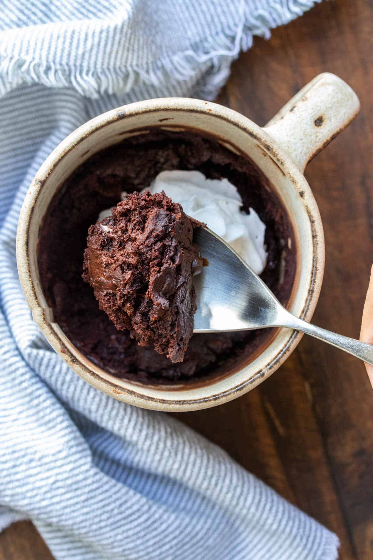 Spoon getting a bite of chocolate cake from a cream mug