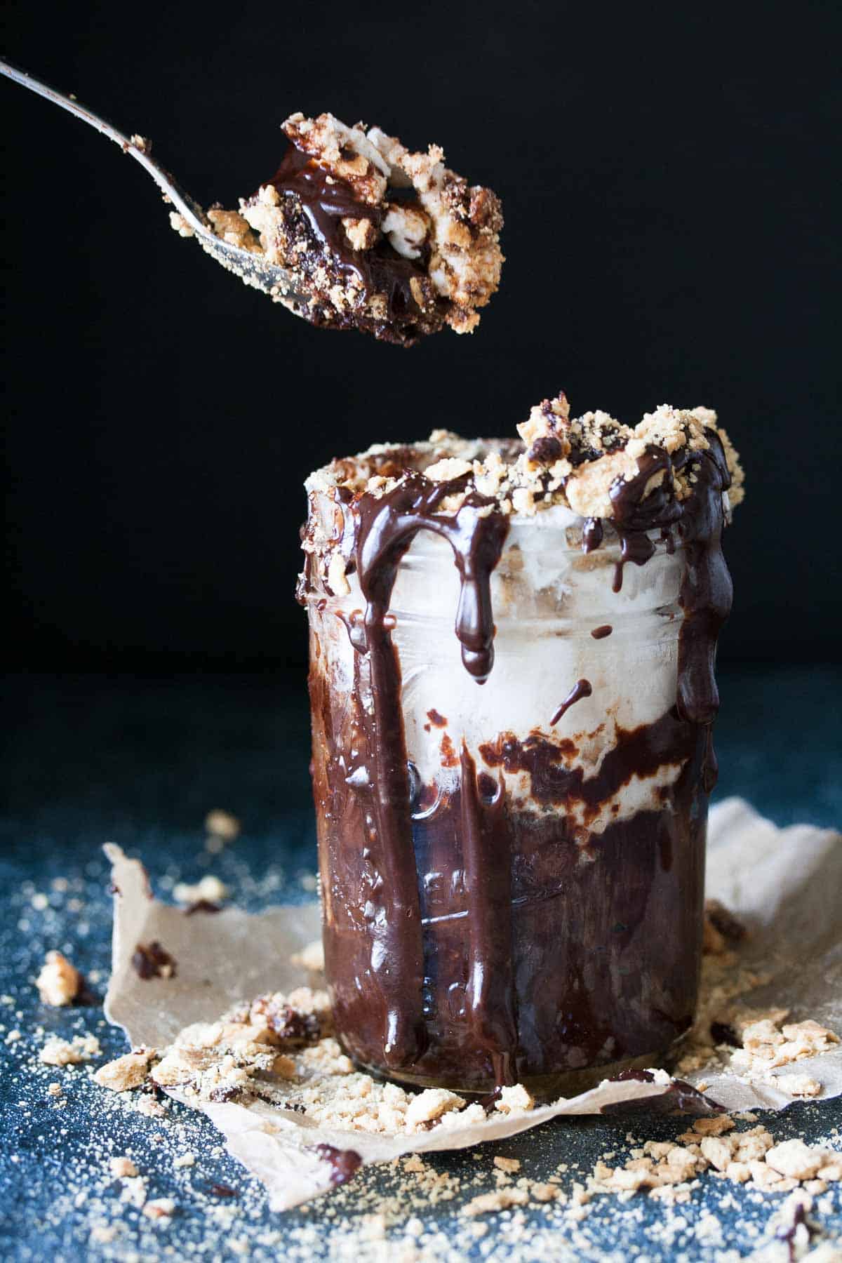 Spoon getting a bite of chocolate cake topped with sauce and toppings from a jar