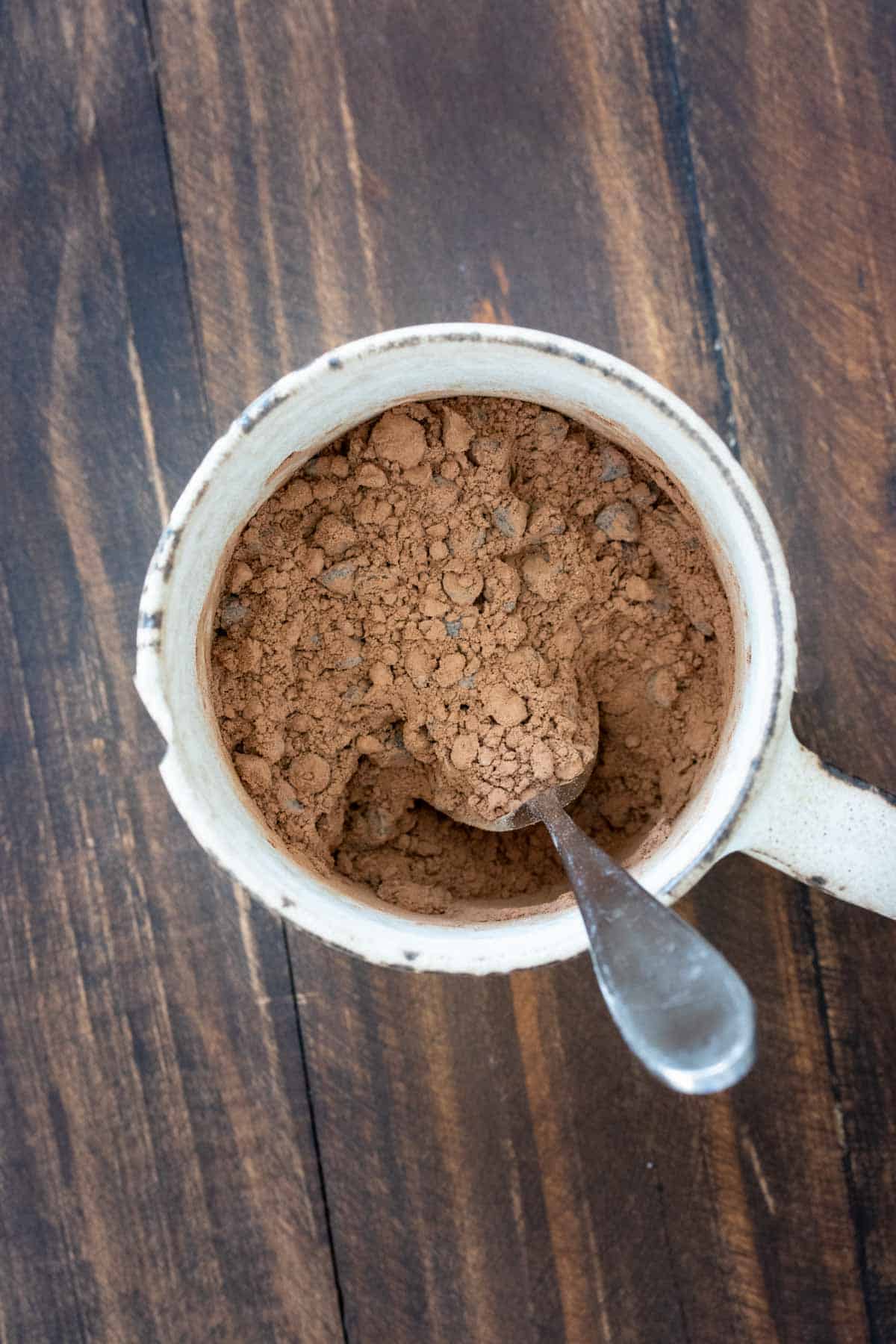 Spoon mixing cocoa powder in a cream mug