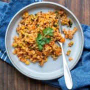 Grey plate on a wooden table filled with Mexican rice and topped with cilantro