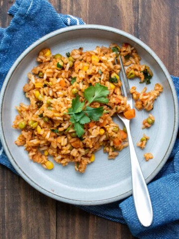 Grey plate with Mexican rice and a fork on a wooden table